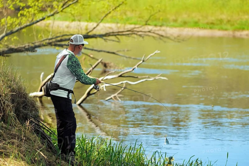 Fisherman trying to do a perfect cast, throwing lure. Spining fishing, angling, catching fish. Hobby and vacation. Photo with shallow depth of field taken at wide open aperture