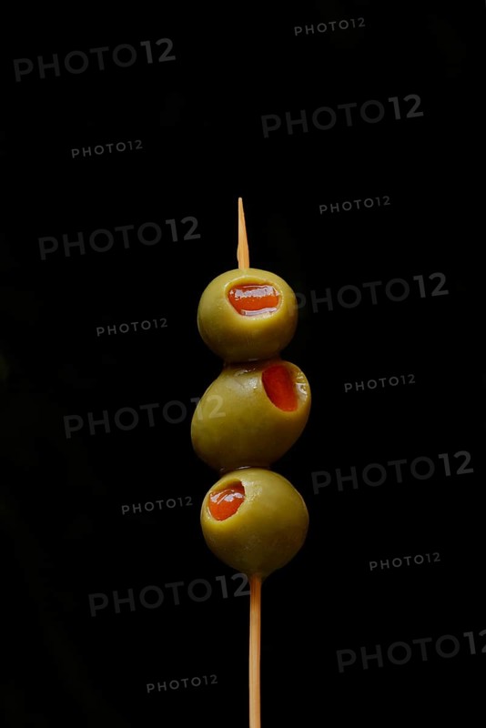 Green olives on fork, stuffed with pieces of paprika