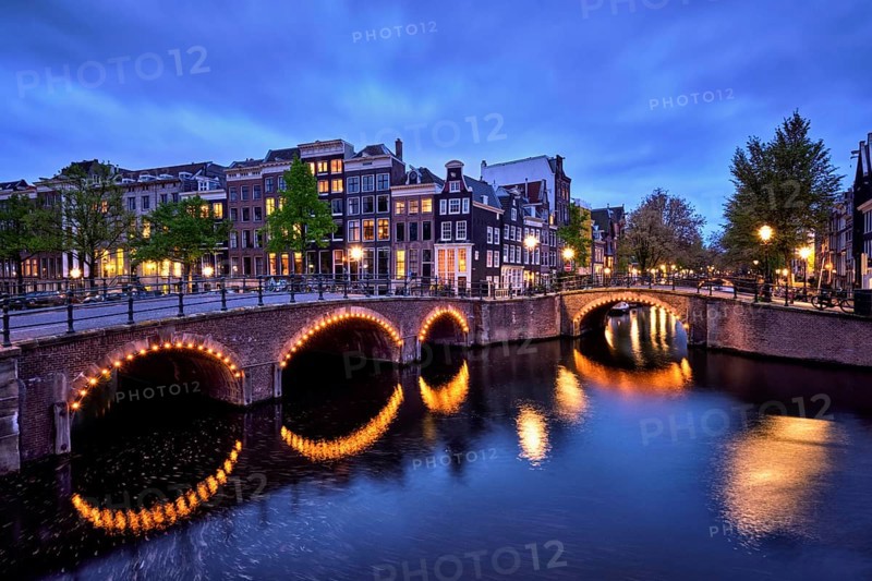 Night view of Amterdam cityscape with canal, bridge and medieval houses in the evening twilight illuminated. Amsterdam, Netherlands