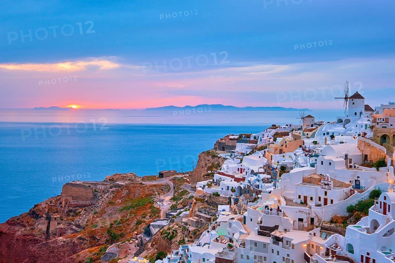 Famous greek iconic selfie spot tourist destination Oia village with traditional white houses and windmills in Santorini island on sunset in twilight, Greece, Europe