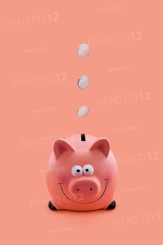 Pink piggy bank with coins falling down