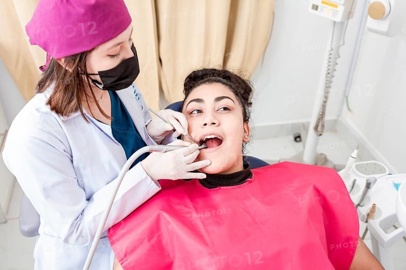 A dentist cleaning a patient mouth with a drill. Stomatologist cleaning a patient's teeth, Close-up of a stomatologist cleaning a woman's teeth, Stomatologist cleaning caries with drill