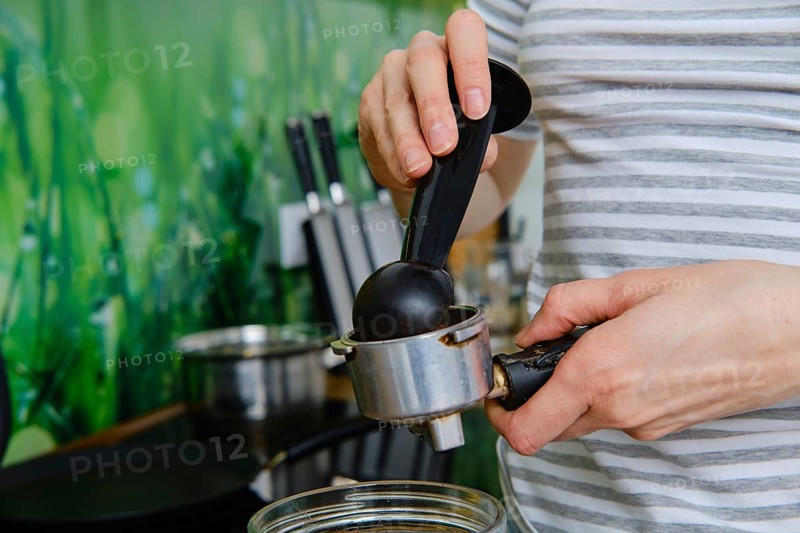Closeup view of female hands making ground coffee in coffee machine