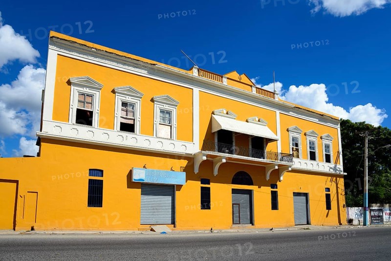 Two-storey yellow building under a clear blue sky with closed shop fronts, Church of Christ, connected to the Ministry, San Pedro de Macoris, Dominican Republic, Hispaniola, Caribbean, Central America