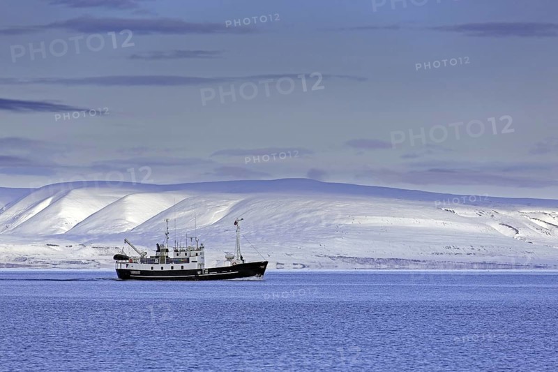 Snow covered mountains and boat with tourists during fjord-cruise in Billefjorden in autumn, Svalbard, Spitsbergen, Norway, Europe