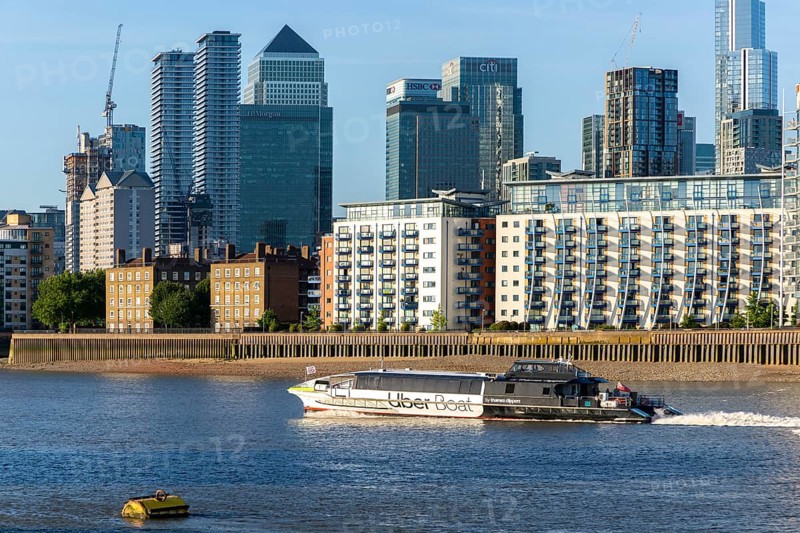 Uber boat water bus service passing Canary Wharf, Isle of Dogs, London, England, UK