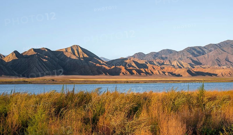 Blue Toktogul reservoir between dry mountain landscape, hilly mountains in the evening light, Jalalabad region, Kyrgyzstan, Asia