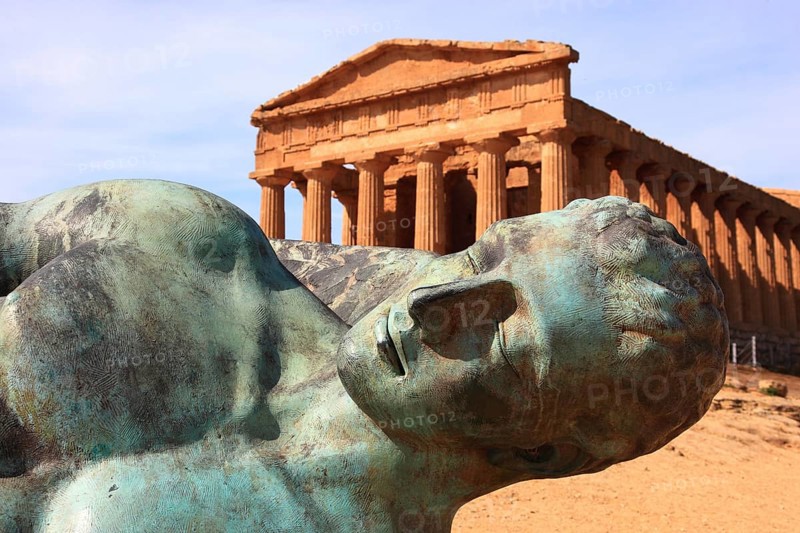 In the Parco Valle dei Templi di Agrigento, Unesco World Heritage Site, remains of the ancient city of Akragas in the Valley of the Temples of Agrigento, the Temple of Concordia with the sculpture of the dismounted Icarus by artist Igor Mitorgi, installed in 2012, Sicily, Italy, Europe