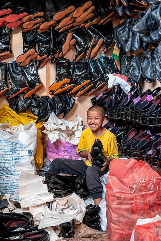 Boy selling shoes, shoe seller, many shoes, market stall, Uzgen Bazaar, Ösgön, Osh region, Kyrgyzstan, Asia