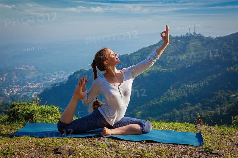Yoga outdoors, young woman doing stretching yoga asana Eka pada rajakapotasana, one-legged king pigeon pose in Himalayas mountains, India, Asia