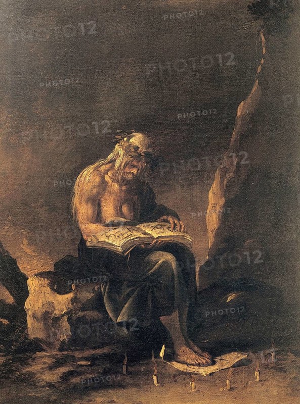 An old witch sits on a rock and reads in a magic book. Around her feet a magic circle of candles, Historic, digitally restored reproduction from an original of the time