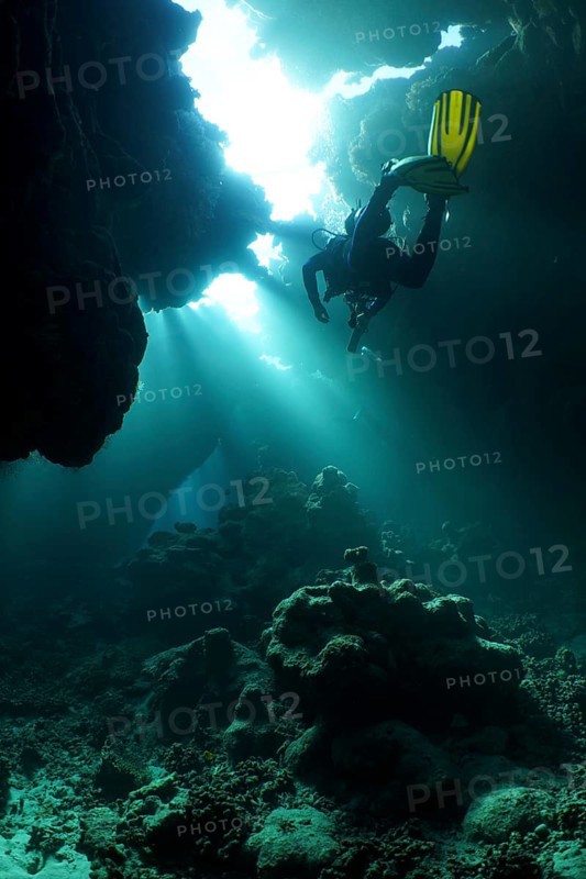 Diver swimming in cave, underwater, light rays, sun rays, St Johns Caves dive site, Saint Johns Reef, Red Sea, Egypt, Africa