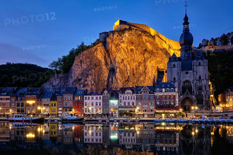 Night view of Dinant town, Collegiate Church of Notre Dame de Dinant over River Meuse and Pont Charles de Gaulle bridge and Dinant Citadel illuminated in the evening. Dinant, Belgium, Europe