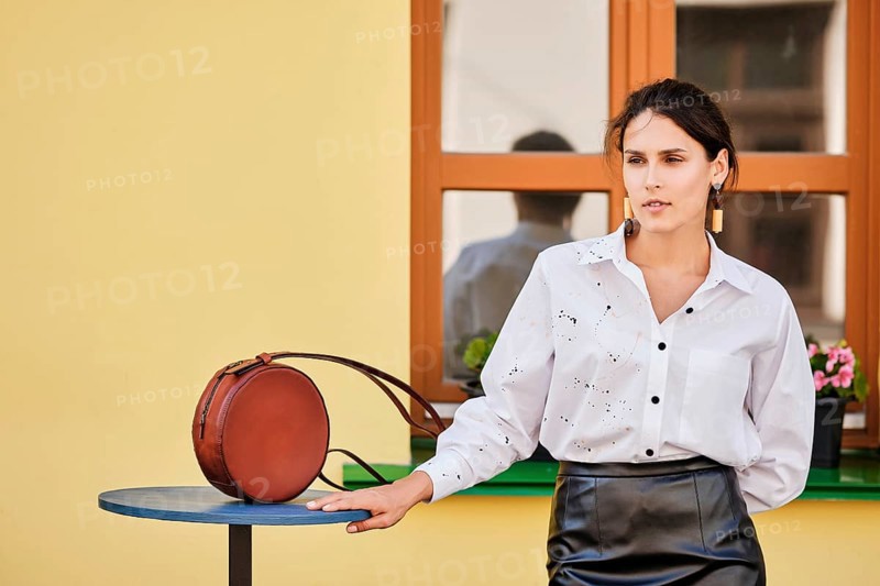 City portrait of elegant lady in leather skirt and white shirt with leather hand bag