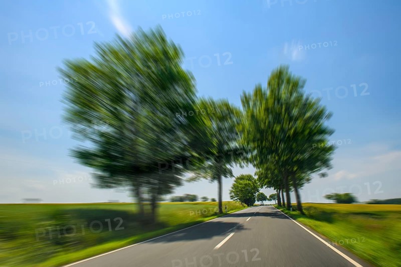 Dynamic photo with speed effect of driving on country road avenue with high speed speeding by speeders without speed limit, Germany, Europe
