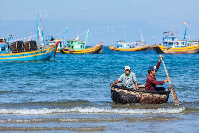 PHAN THIET, VIETNAM, 5 JUNE, 2011: Two fishermen in a coracle boat returning from fishing. Phan Thiet is a coastal city famous for its tourism district Mui Ne and seafood as well as sea products