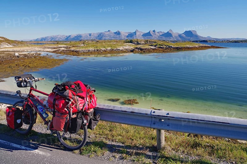 Packed touring bike, crystal clear water in a shallow bay, view of the mountain range Seven Sisters, cycle tourism, cycle trip, Heröy Island FV 17, Kystriksveien, Nordland, Norway, Europe