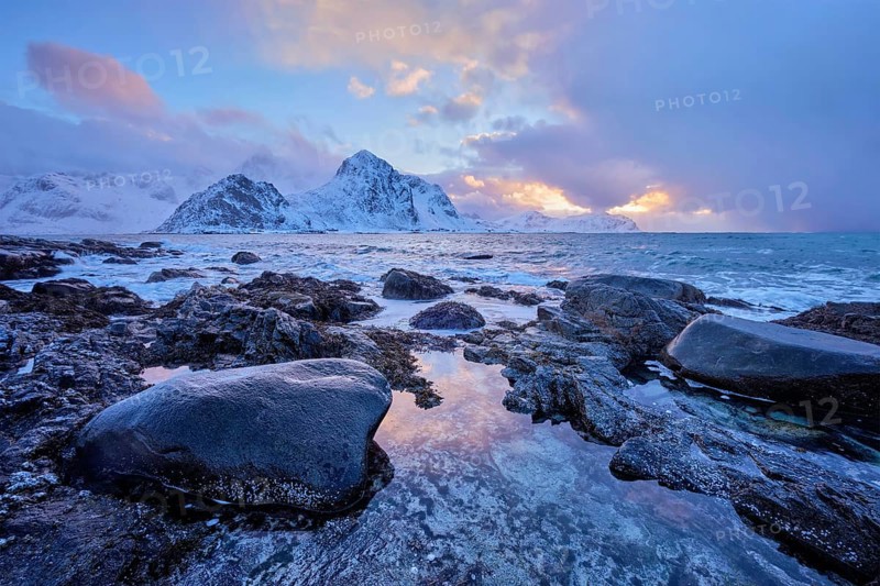 Beach of Norwegian sea on rocky coast in fjord on sunset in winter. Vareid beach, Lofoten islands, Norway, Europe