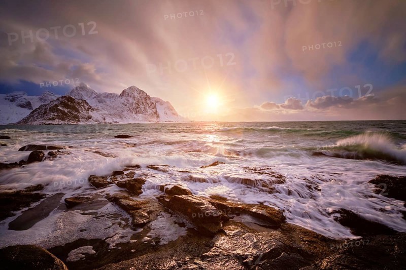 Beach of Norwegian sea on rocky coast in fjord on sunset in winter. Vareid beach, Lofoten islands, Norway, Europe