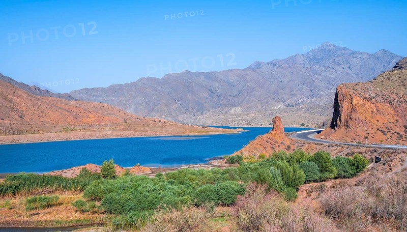 Blue Toktogul reservoir between dry mountain landscape with red mountains, Jalalabad region, Kyrgyzstan, Asia