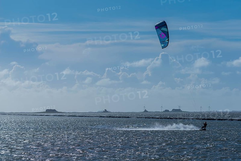 Kitesurfing on the North Sea, Lüttmoorsiel, Reußenköge, on the horizon Hallig Nordstrandischmoor, Lorendamm, wind power, wind force 6, blue sky, North Frisia, Schleswig-Holstein, Germany, Europe