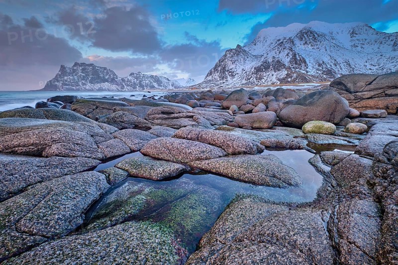 Rocks on beach of fjord of Norwegian sea in winteron sunset. Utakliev beach, Lofoten islands, Norway, Europe