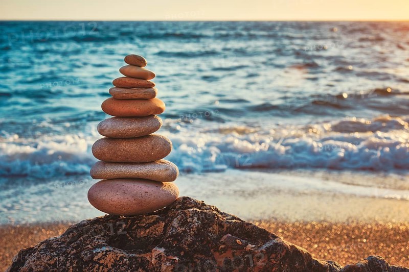 Concept of balance and harmony. Cairn stack of stones pebbles cairn on the beach coast of the sea in the nature on sunset. Meditative art of stone stacking