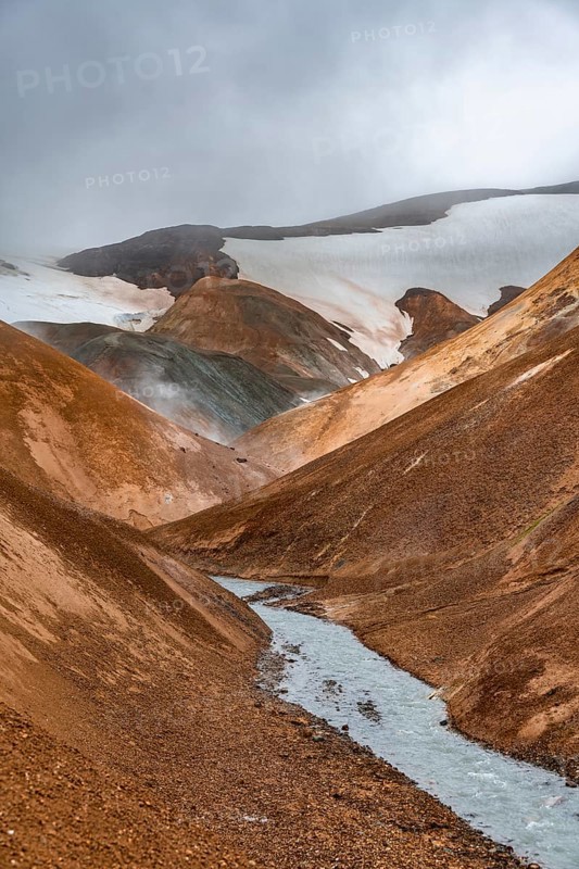 Steaming stream between colourful rhyolite mountains and snowfields, Hveradalir geothermal area, Kerlingarfjöll, Icelandic Highlands, Iceland, Europe