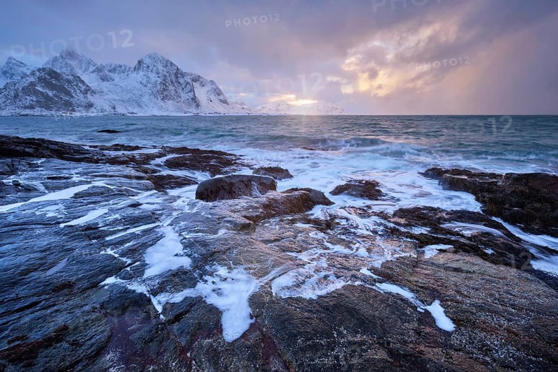 Beach of Norwegian sea on rocky coast in fjord on sunset in winter. Vareid beach, Lofoten islands, Norway, Europe