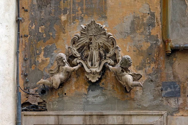 Putti holding an ecclesiastical symbol above an entrance door to a crypt, historic centre, Piazza Pinelli, Genoa, Italy, Europe