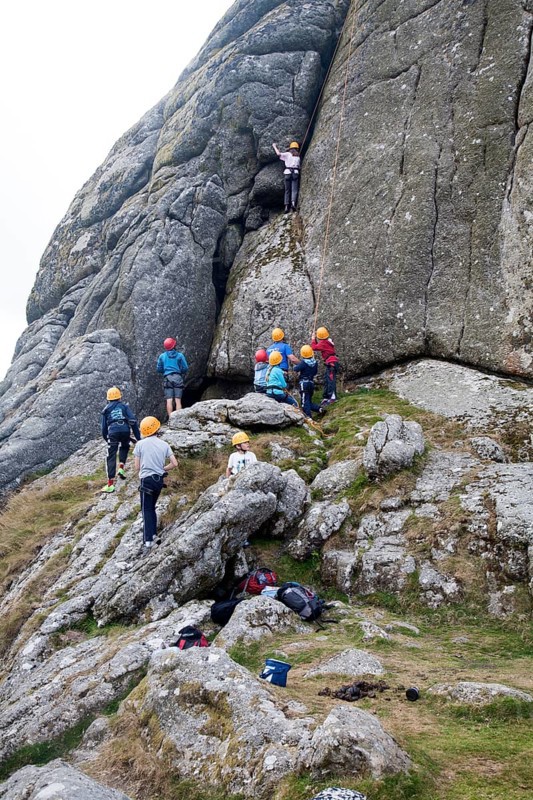 Children rock climbing on the granite tor of Haytor, Dartmoor national park, Devon, England, UK