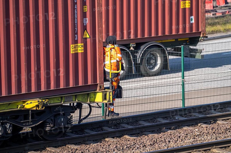 Shunter, railway employee steering the freight train with containers from the running board of the freight wagon on the goods train line to, from HHLA Container Terminal Burchardkai, Hamburg, Germany, Europe