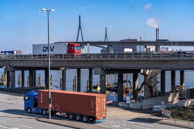 The Köhlbrand Bridge in the Port of Hamburg, rear, front trucks on the Waltershoferdam, access to the HHLA Container Terminal Burchardkai, middle traffic on the A7 motorway, spans the 325 m wide Köhlbrand, an arm of the Süderelbe, the bridge is over 3600 metres long, 53 metres above the water, piers 135 m high, more than 30, 000 vehicles use the B3 bridge daily, important connection to the port, it is dilapidated, is to be rebuilt, Hamburg, Germany, Europe