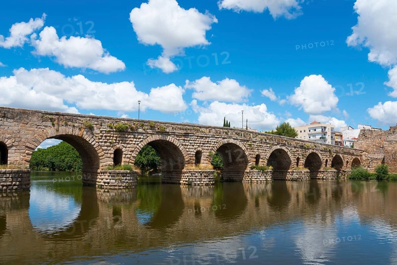 Ancient stone bridge with reflections in the river water, under blue sky with some clouds, Roman bridge, Puente Romano, arch bridge with wedge stone vault, river Guadiana, Mérida, Merida, Badajoz, Extremadura, Spain, Europe