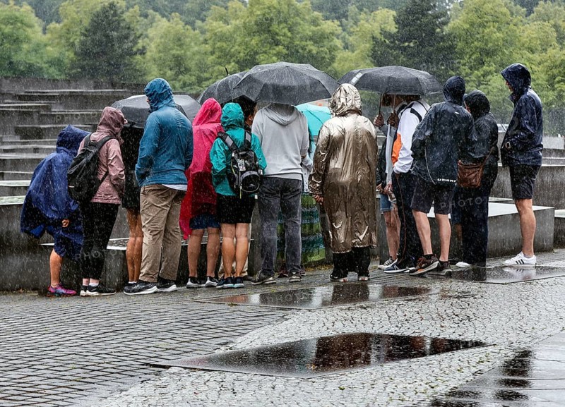 Visitors to the Memorial to the Murdered Jews of Europe protect themselves from heavy rainfall with umbrellas, Berlin, 23 June 2023