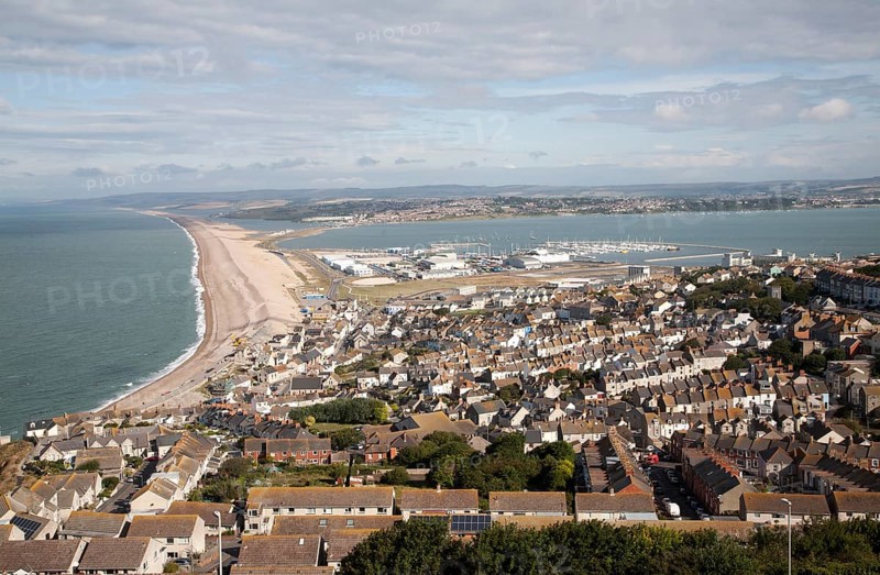 Chesil beach tombolo with housing in Chiswell in the foreground, Isle of Portland, Dorset, England, UK