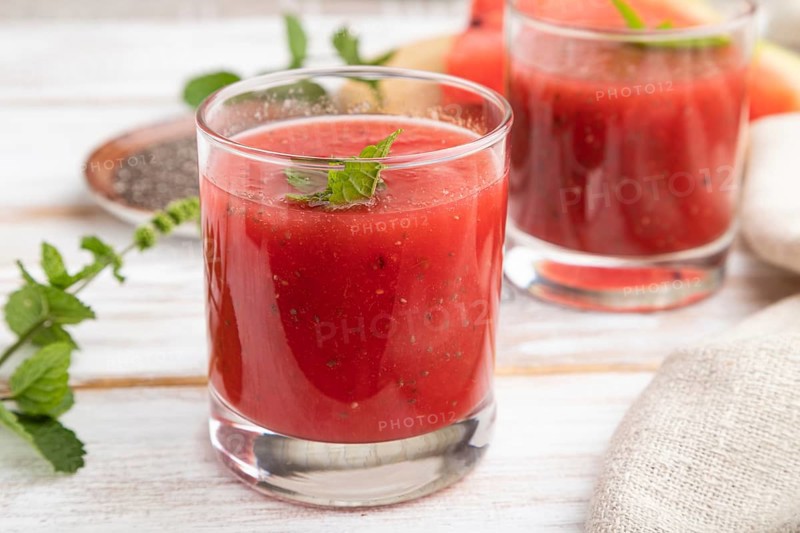 Watermelon juice with chia seeds and mint in glass on a white wooden background with linen textile. Healthy drink concept. Side view, close up