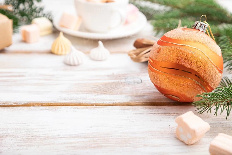 Christmas or New Year composition. Decorations, box, balls, cinnamon, fir and spruce branches, cup of coffee, on a white wooden background. Side view, copy space, selective focus