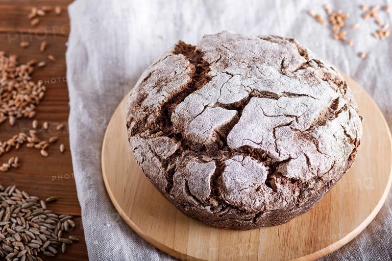 Yeast free homemade bread with whole rye and wheat grains on rustic wooden background. close up