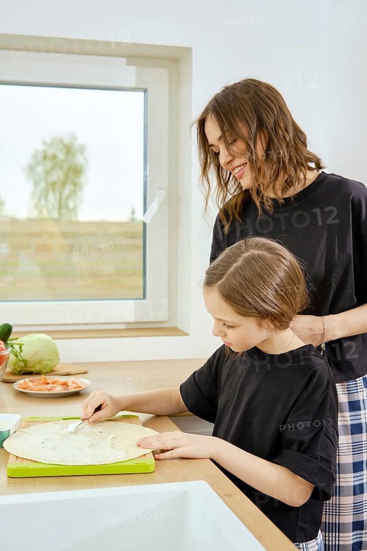 The mother entrusted her daughter to prepare a snack for breakfast, stands nearby and watches her actions