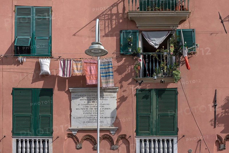 Residential building façade with green shutters and hanging laundry in the historic city centre, Genoa, Italy, Europe