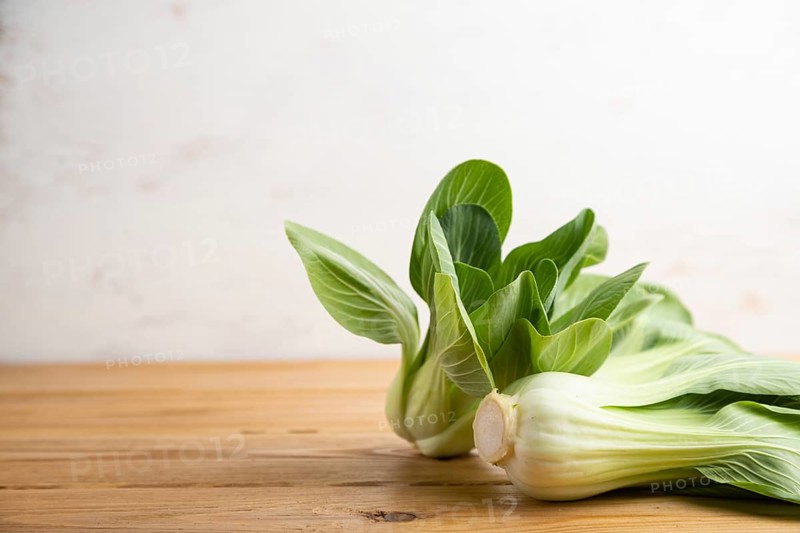 Fresh green bok choy or pac choi chinese cabbage on a brown wooden background. Side view, copy space, selective focus