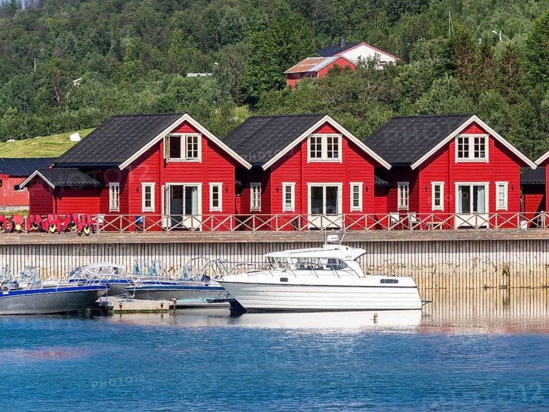 Typical red-white wooden holiday cottages, pier with leisure boats, Lenangsstraumen, Lyngen peninsula, Norway, Europe