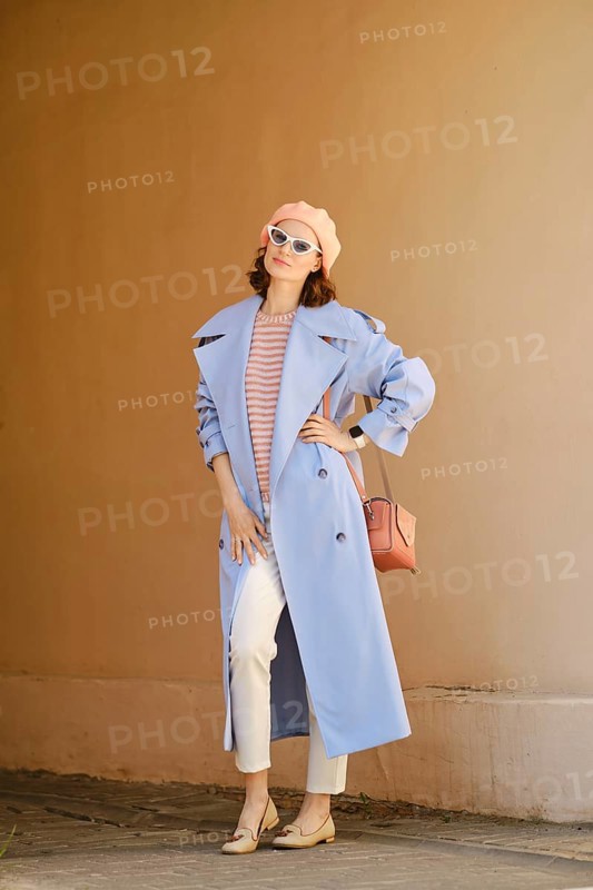 Trendy woman in long blue trench coat posing outdoors