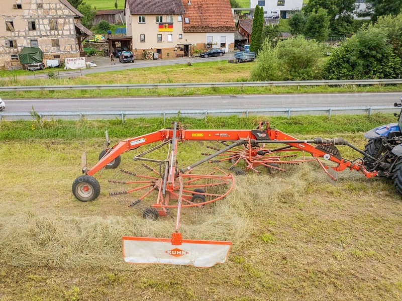 Close-up of a haymaking machine in a field, with a building and a road in the background, Dachtel. Black Forest, Germany, Europe