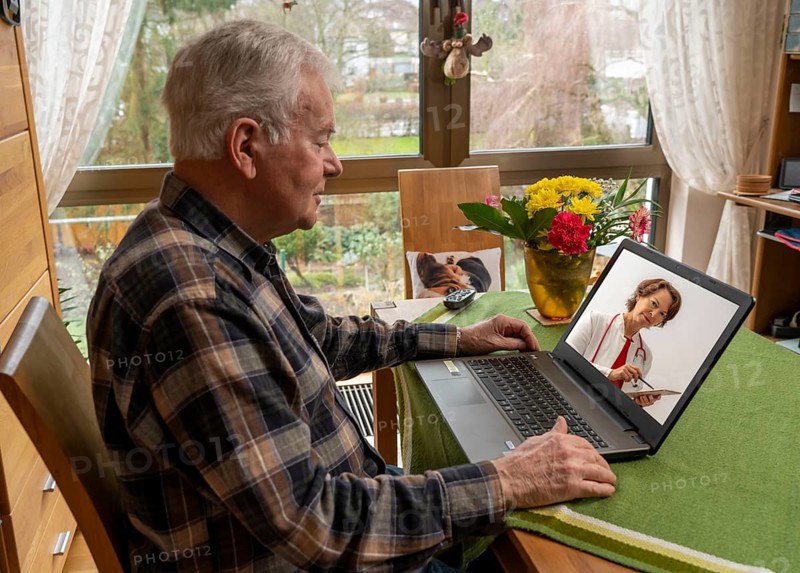 Symbolic image of telemedicine, elderly patient speaking to a doctor in a video conference from home