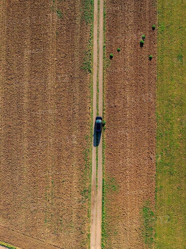 Aerial view of a car on a narrow country lane between green and brown fields on a clear day, car sharing, VW ID5, Calw, Black Forest, Germany, Europe