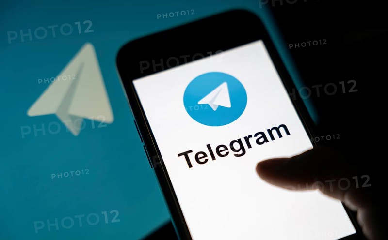 The social media Telegram messenger logo is being displayed on a smartphone screen and on a computer screen