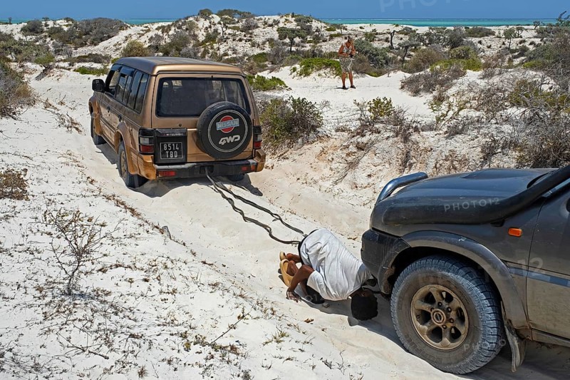 Four-wheel drive vehicle towing 4X4 SUV car in loose sand while driving off-road along the Malagasy west coast, Atsimo-Andrefana Region, Madagascar, Africa