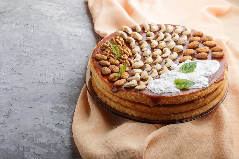 Homemade cake with caramel cream and nuts on a gray concrete background. side view, copy space